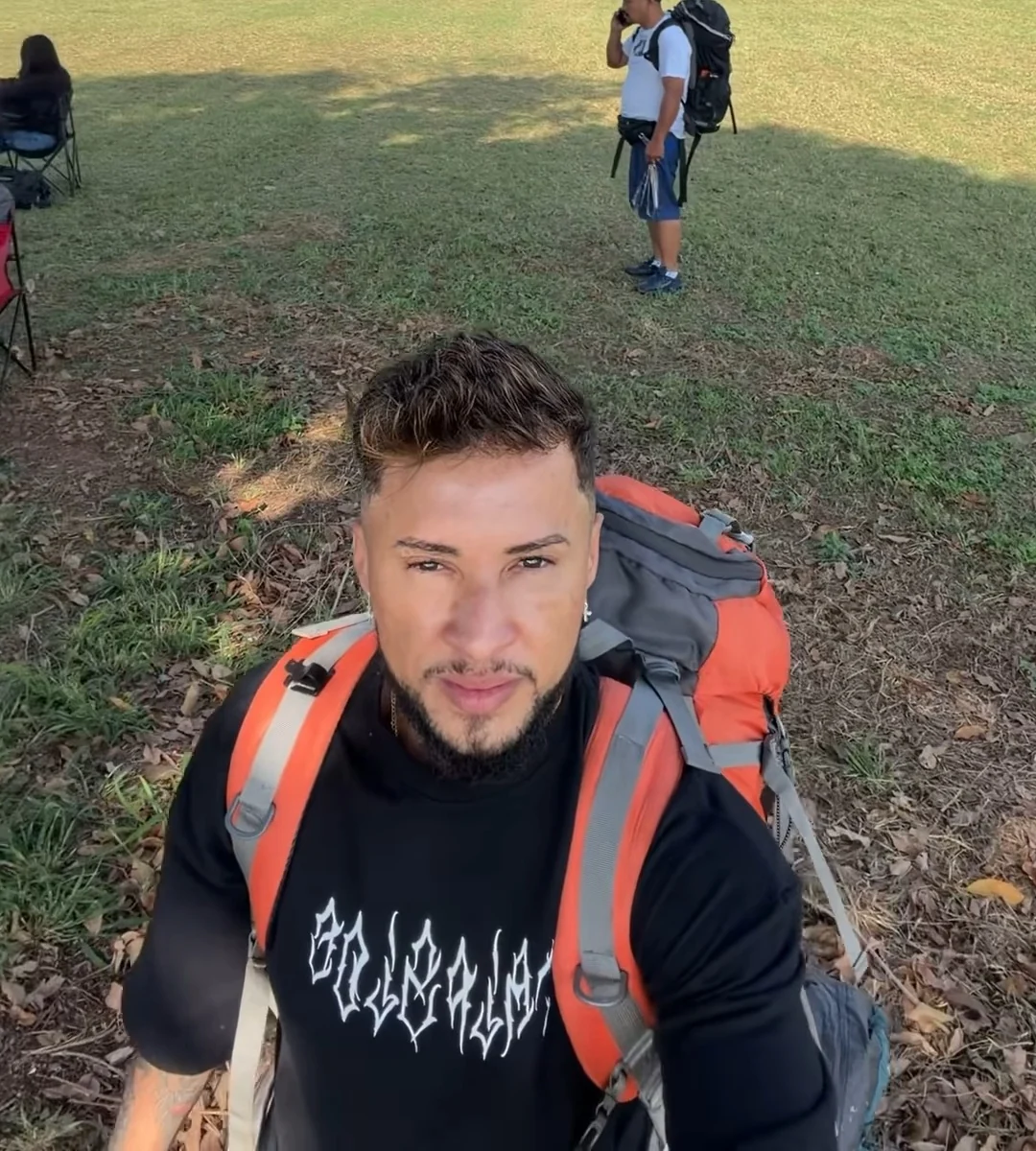 Eduardo Capelo ao ar livre com mochila de camping laranja